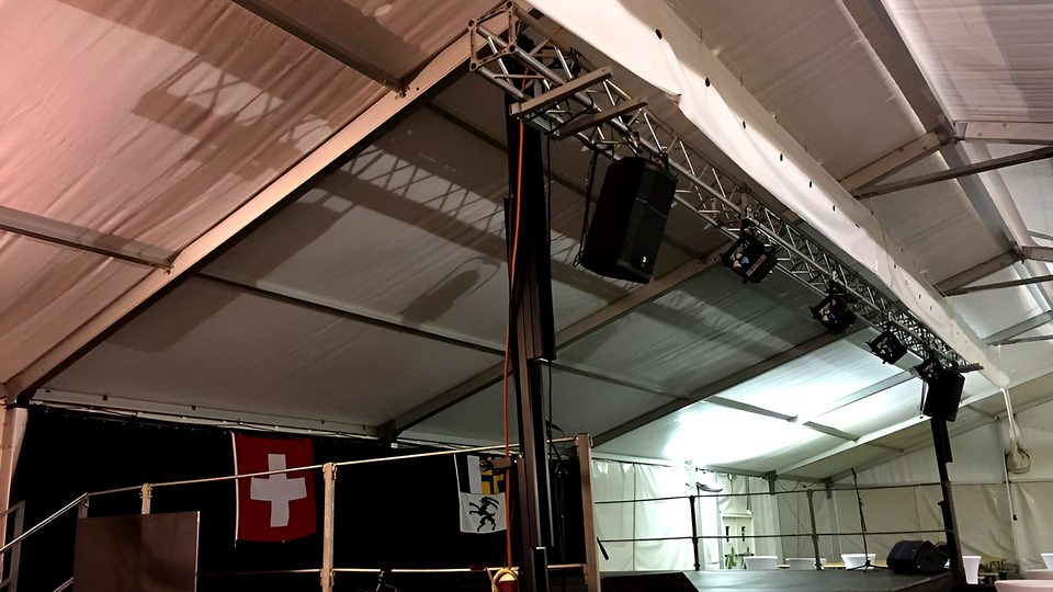 Palco dentro una tensostruttura con traliccio, casse, fari, parapetti e le bandiere svizzera e grigionese